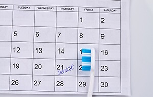 Toothbrush on calendar, next to reminder for dental checkup