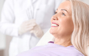 a patient smiling after receiving all-on-4 dental implants