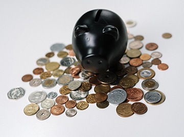 Black piggy bank with loose coins