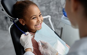 Child smiling in dental chair during checkup and cleaning in Jacksonville 