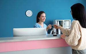 Woman using card to make payment in dental office