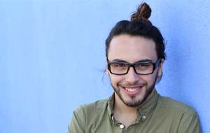 man with glasses smiling in front of a blue background