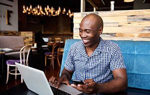 person smiling and doing research on their laptop