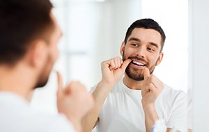 Man flossing his teeth at home