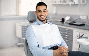 Man in blue shirt smiling in dentist's treatment chair