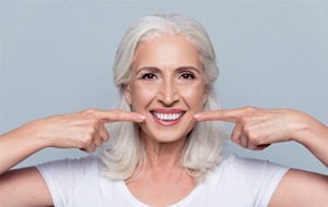 Older woman pointing to her smile