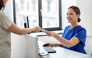 Smiling dental team member accepting card for payment