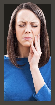 Woman in blue blouse holding the side of her face in pain