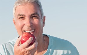 Smiling older man holding a red apple