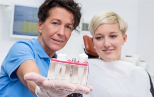 Dentist showing patient dental implant model