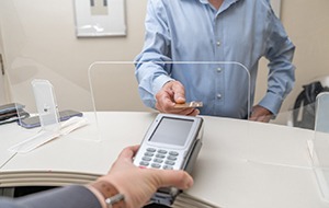 An adult man paying for dental care with a credit card