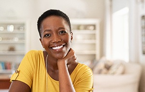 Woman in yellow shirt smiling while sitting in living room
