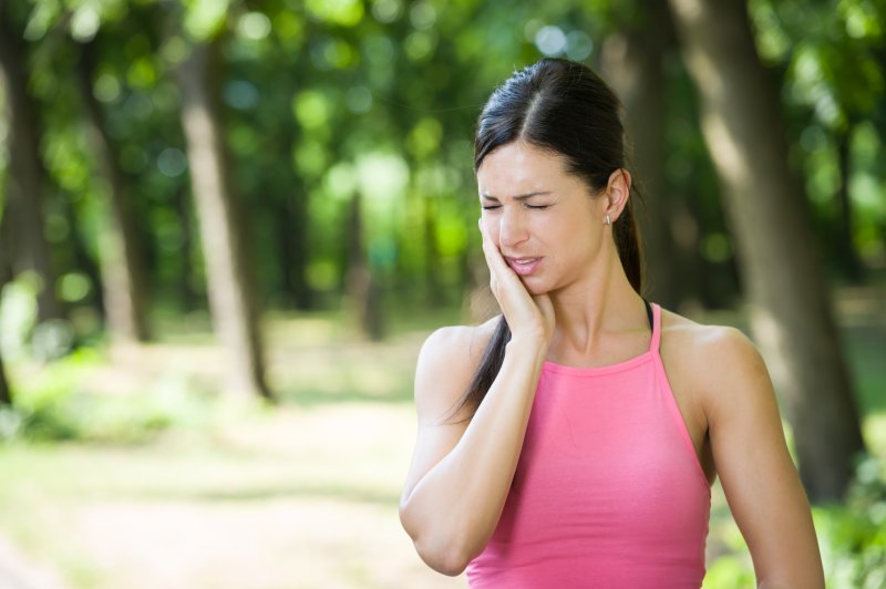 a woman holding her cheek in pain