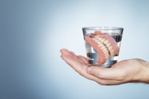 hand holding soaking dentures
