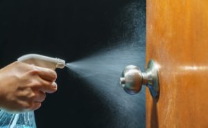 person sanitizing a door handle in a dental practice
