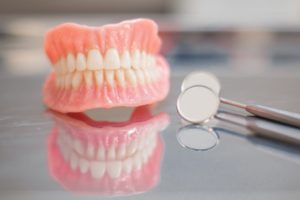 a damaged denture sitting on a countertop next to dental mirrors