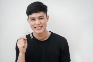 young man holding Invisalign in North Jacksonville 