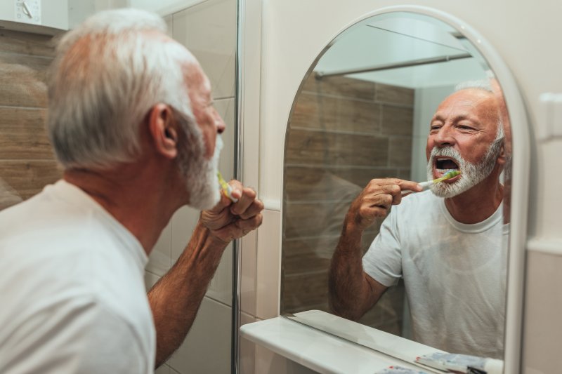 Senior man brushing his teeth in bathroom