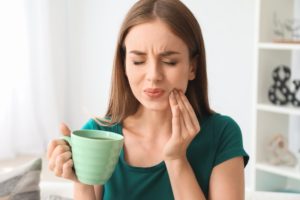 Woman with hand on her cheek experiencing dental pain