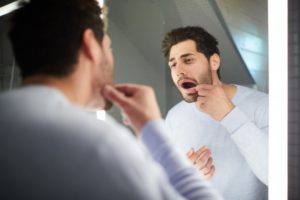 man looking in the mirror at a bump on his gums 