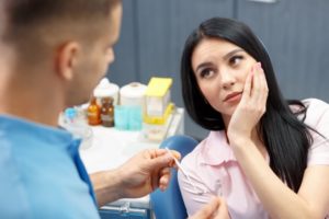 woman with a dental emergency talking to her dentist 