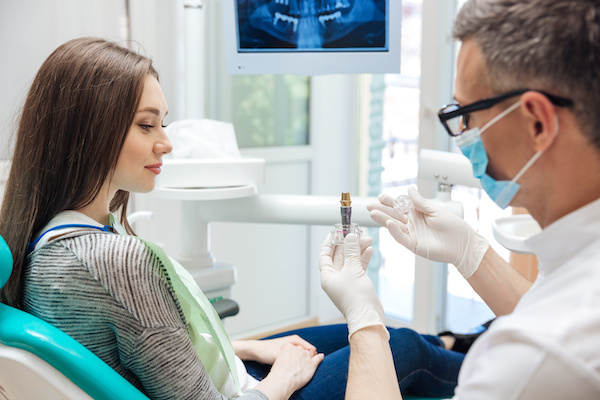 young woman learning about dental implant in dental office