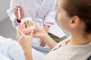 Patient holding a model of dental implants at the dentist’s office.
