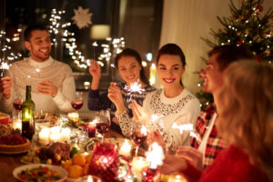 happy friends with sparklers celebrating Christmas at home feast