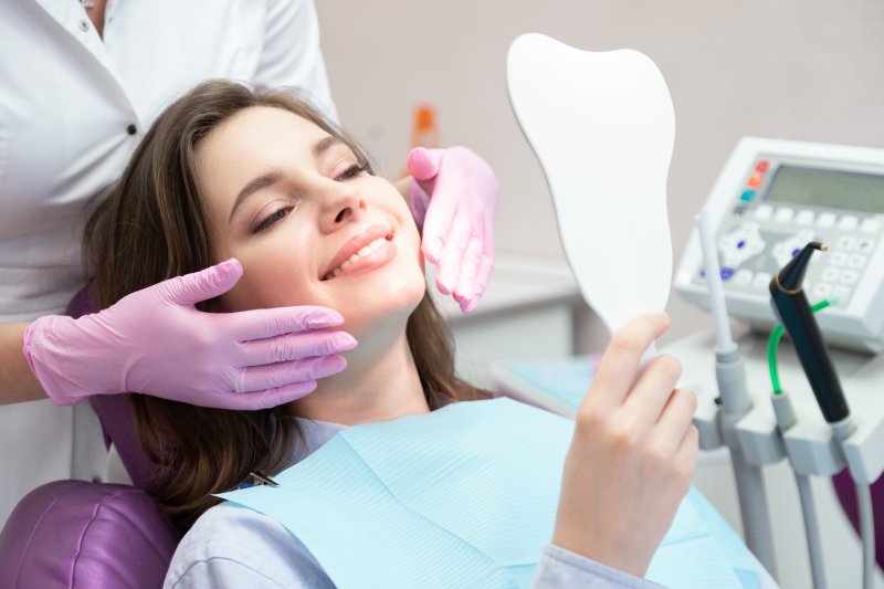 A woman admiring the results of non-invasive cosmetic dentistry